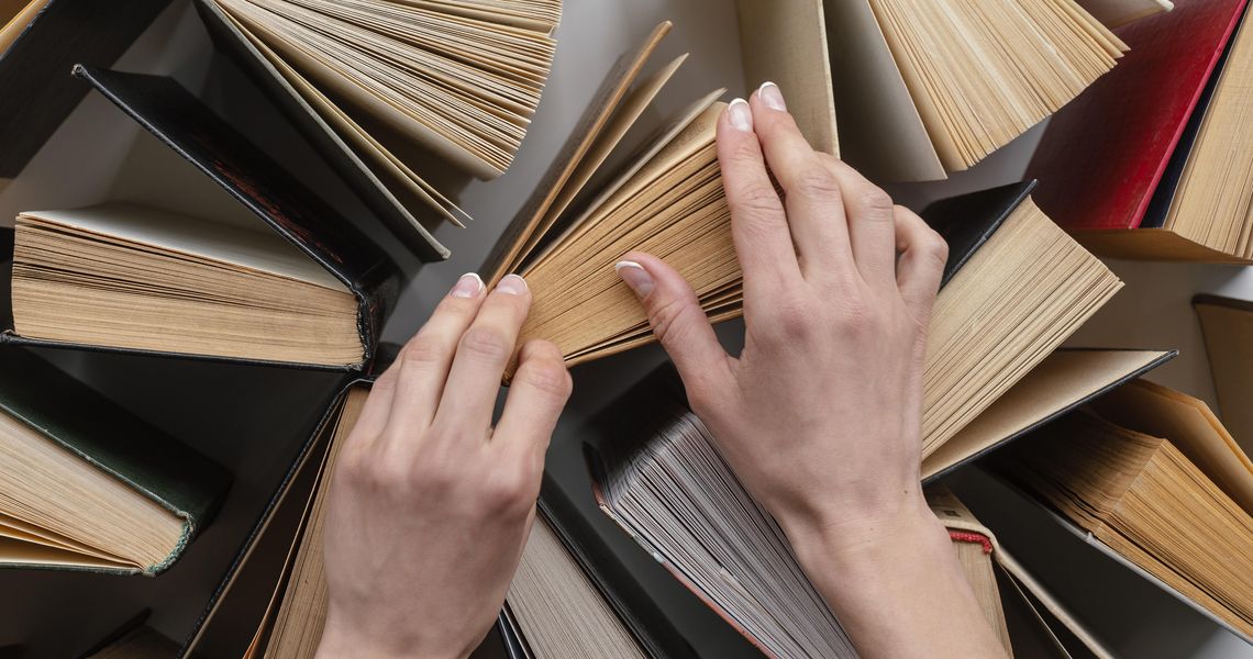 Handen bij een stapel boeken